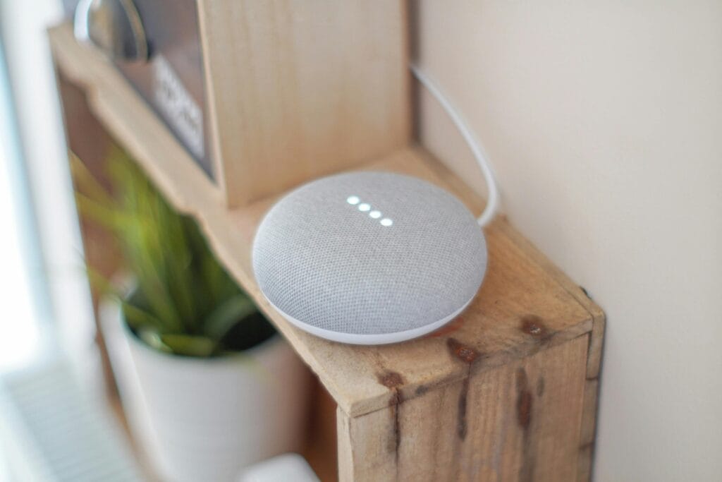 Inteligentny głośnik Google Home Mini na drewnianej półce łączący technologię z wystrojem domu.